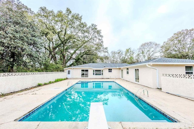 view of swimming pool featuring a diving board, a patio area, a fenced in pool, and fence