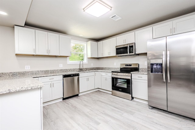 kitchen featuring stainless steel appliances, light wood-style floors, visible vents, and white cabinetry