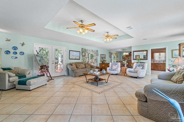 living room with ceiling fan, light tile patterned floors, a textured ceiling, a tray ceiling, and french doors