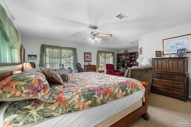 bedroom featuring light carpet, a textured ceiling, and ceiling fan