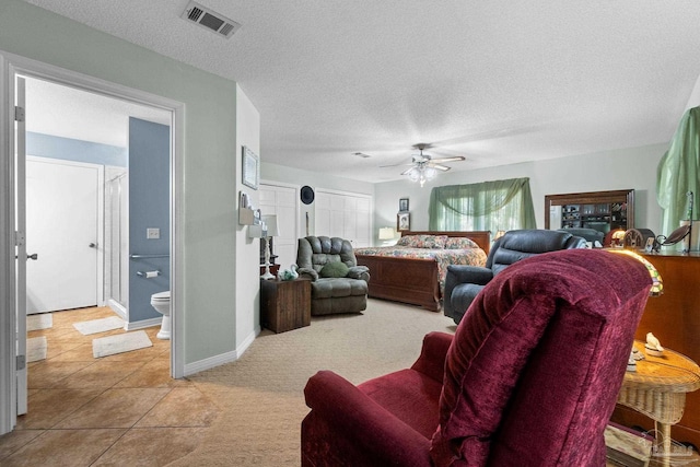 bedroom with ceiling fan, tile patterned floors, a textured ceiling, and ensuite bath