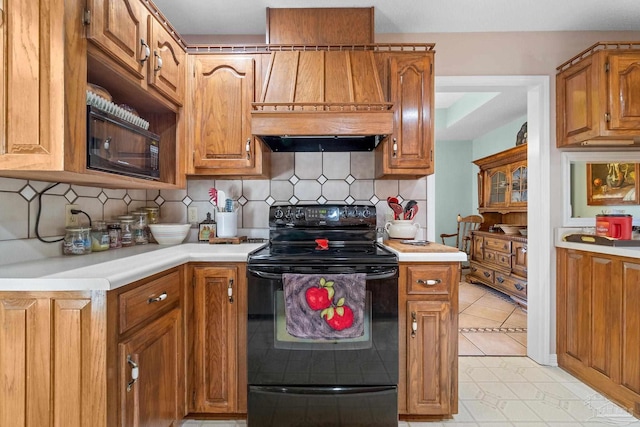 kitchen featuring black range with electric cooktop, light tile patterned flooring, backsplash, and custom exhaust hood