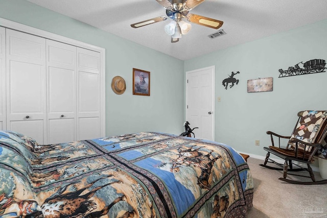 carpeted bedroom with a closet, ceiling fan, and a textured ceiling