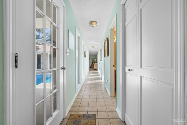 hallway with french doors, light tile patterned flooring, and a textured ceiling