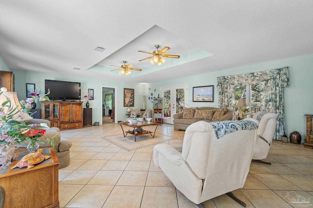 tiled living room featuring a textured ceiling, a tray ceiling, and ceiling fan