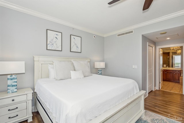 bedroom featuring hardwood / wood-style flooring, crown molding, ceiling fan, and ensuite bath