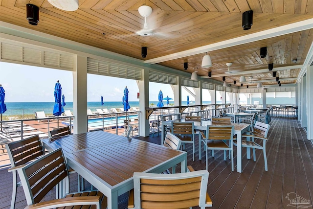 dining area with wood ceiling, a wealth of natural light, dark hardwood / wood-style floors, and a water view