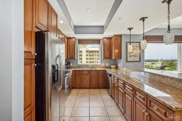 kitchen featuring pendant lighting, light tile patterned floors, stone counters, stainless steel appliances, and a tray ceiling