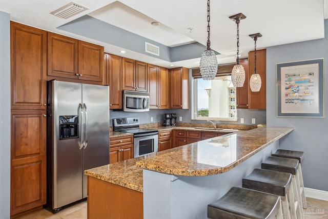 kitchen featuring appliances with stainless steel finishes, pendant lighting, sink, a breakfast bar area, and kitchen peninsula