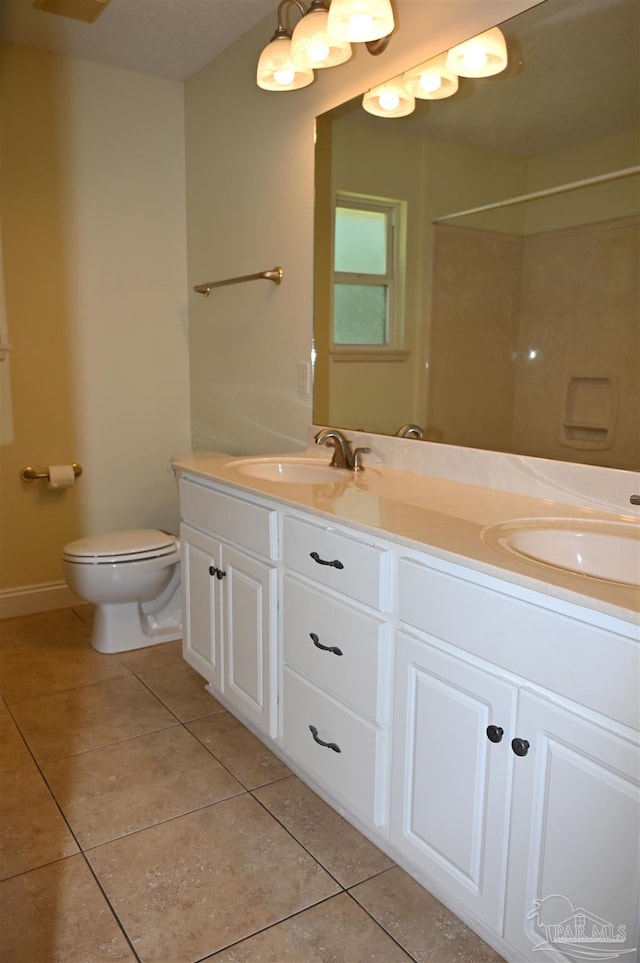 bathroom featuring tile patterned flooring, double vanity, and toilet