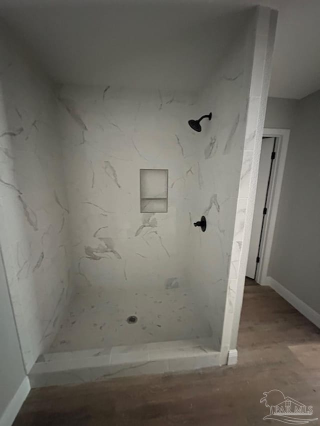 bathroom with baseboards, a marble finish shower, and wood finished floors