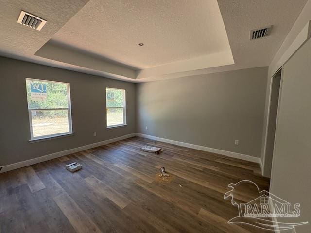 empty room featuring baseboards, visible vents, and a raised ceiling