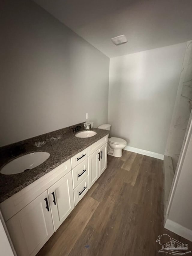 bathroom featuring toilet, baseboards, a sink, and wood finished floors