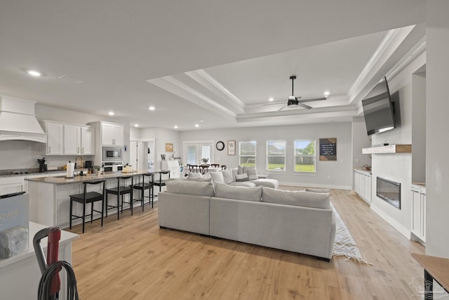 5534 Blake Ln, Pace, FL 32571 - living room with a glass covered fireplace, recessed lighting, light wood-style flooring, a ceiling fan, and a raised ceiling