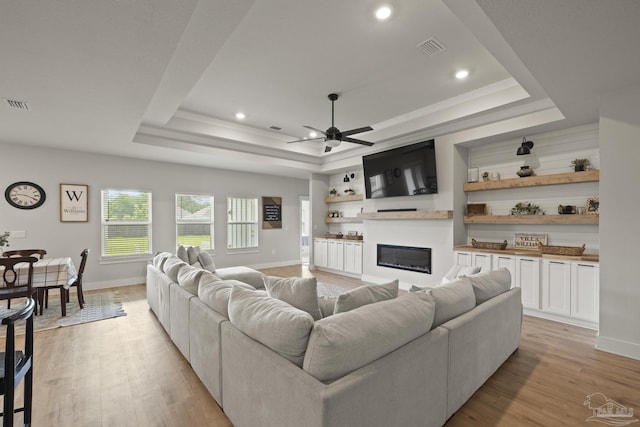 5534 Blake Ln, Pace, FL 32571 - living area featuring a tray ceiling, ceiling fan, light wood finished floors, a glass covered fireplace, and baseboards