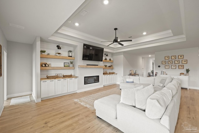 5534 Blake Ln, Pace, FL 32571 - living room featuring a tray ceiling, a ceiling fan, light wood-style flooring, a glass covered fireplace, and recessed lighting