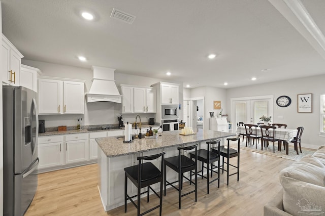 5534 Blake Ln, Pace, FL 32571 - kitchen featuring stainless steel appliances, custom range hood, white cabinetry, recessed lighting, and a breakfast bar
