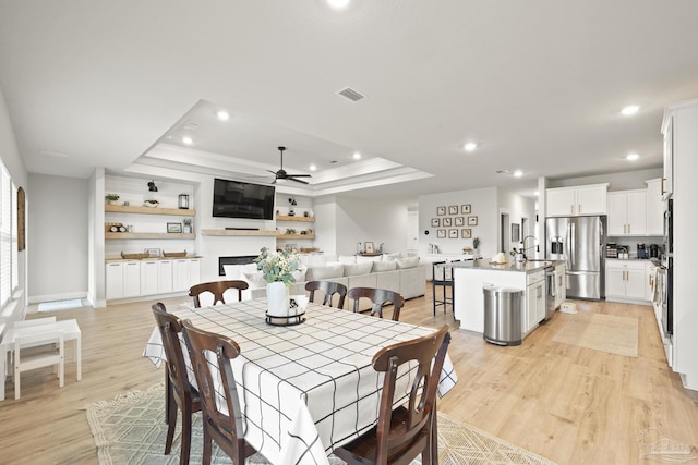 5534 Blake Ln, Pace, FL 32571 - dining room with a tray ceiling, a ceiling fan, recessed lighting, light wood-style flooring, and a fireplace