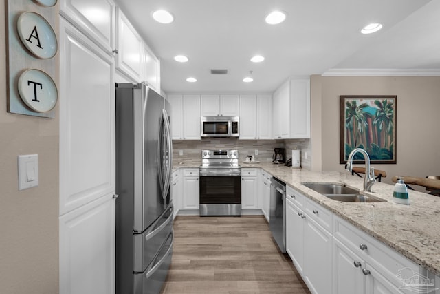 kitchen featuring tasteful backsplash, stainless steel appliances, sink, light hardwood / wood-style floors, and ornamental molding