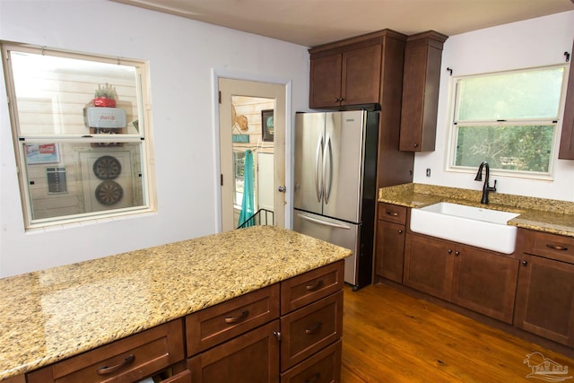 kitchen featuring a sink, light stone counters, dark wood-type flooring, and freestanding refrigerator