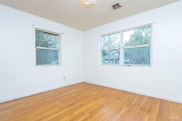 spare room with a wealth of natural light, baseboards, visible vents, and light wood finished floors