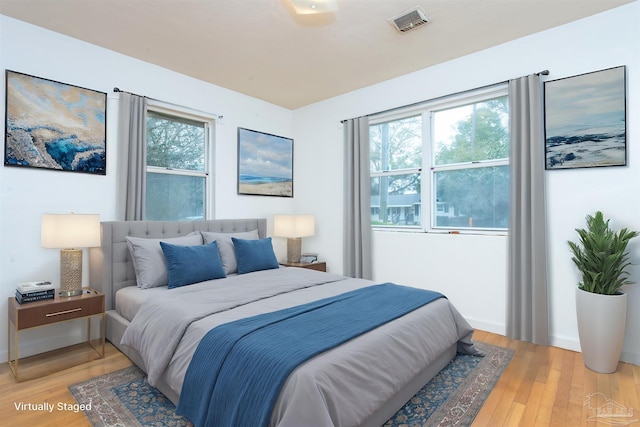 bedroom featuring baseboards, visible vents, and light wood finished floors