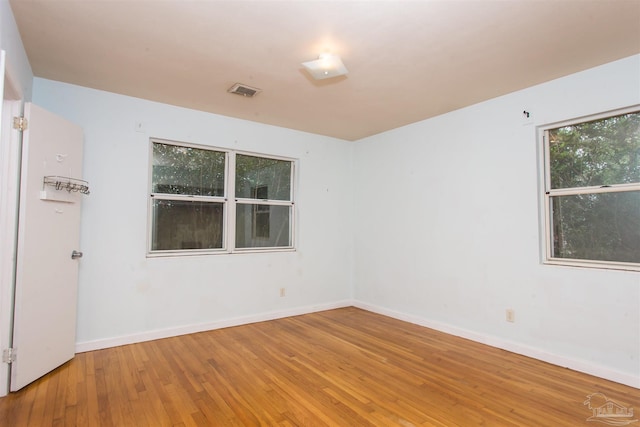 empty room with visible vents, baseboards, and hardwood / wood-style flooring