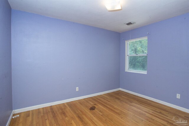 unfurnished room with baseboards and wood-type flooring