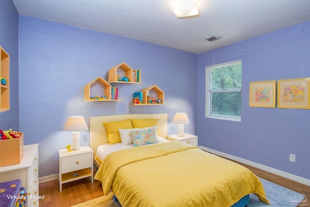 bedroom with visible vents, wood finished floors, and baseboards