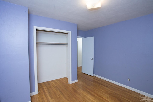 unfurnished bedroom with a closet, baseboards, and wood finished floors