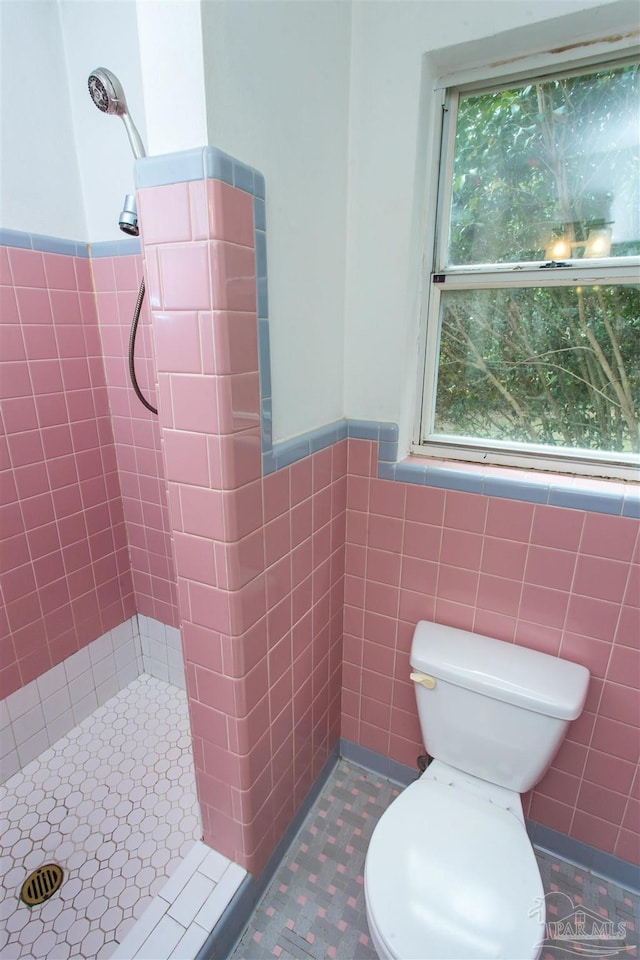 full bath with a shower stall, toilet, tile walls, and a wainscoted wall