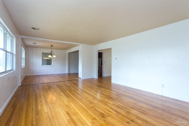 unfurnished living room featuring light wood finished floors and a notable chandelier