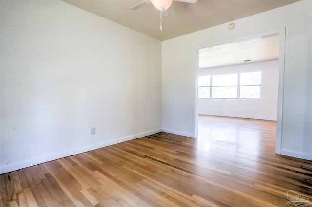 empty room featuring a ceiling fan, baseboards, and hardwood / wood-style flooring