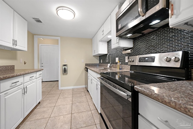 kitchen with dark stone counters, tasteful backsplash, a sink, white cabinetry, and appliances with stainless steel finishes
