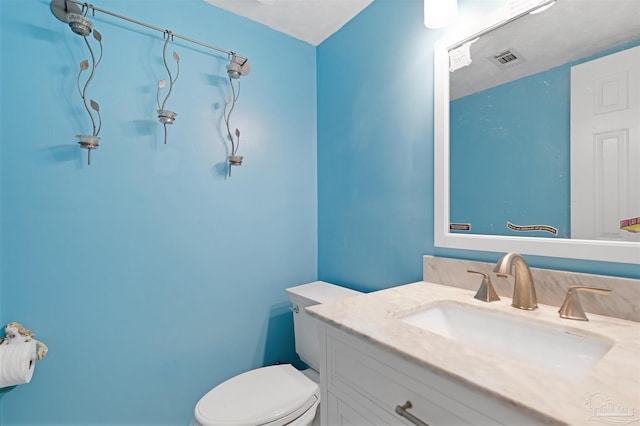 bathroom with visible vents, vanity, and toilet