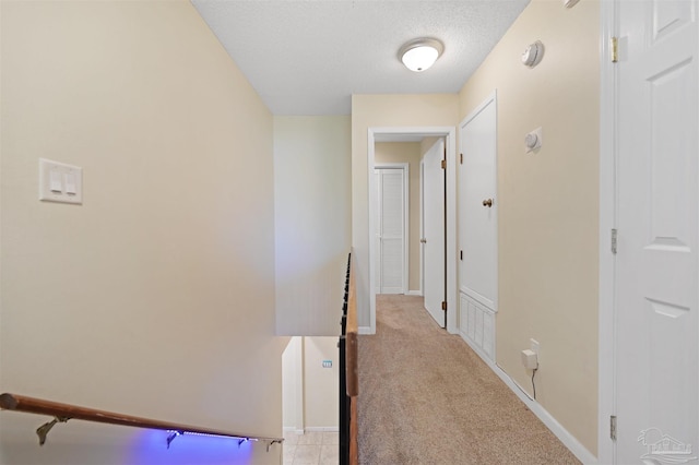 hallway with baseboards and light colored carpet