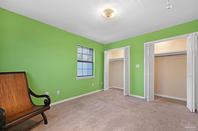 living area with baseboards, carpet flooring, and a textured ceiling