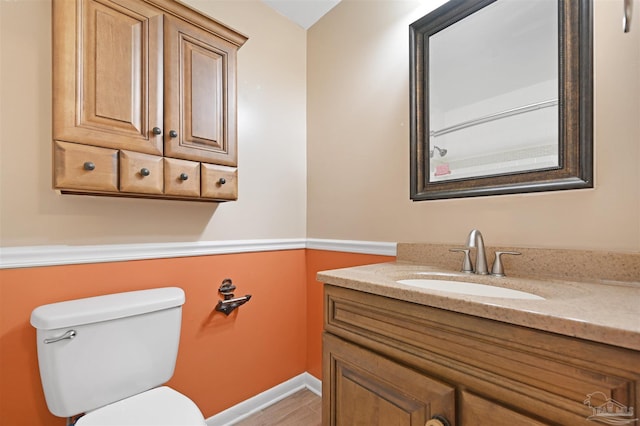 bathroom featuring toilet, vanity, and baseboards