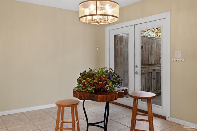 entryway featuring baseboards, a chandelier, and light tile patterned floors