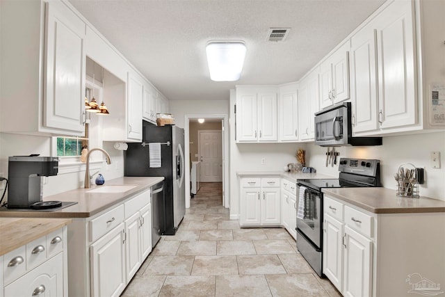 kitchen featuring white cabinetry, stainless steel appliances, sink, and a textured ceiling