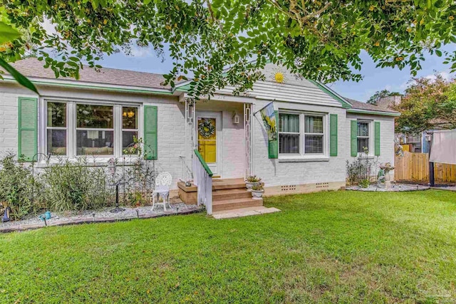 view of front facade featuring crawl space, brick siding, fence, and a front lawn