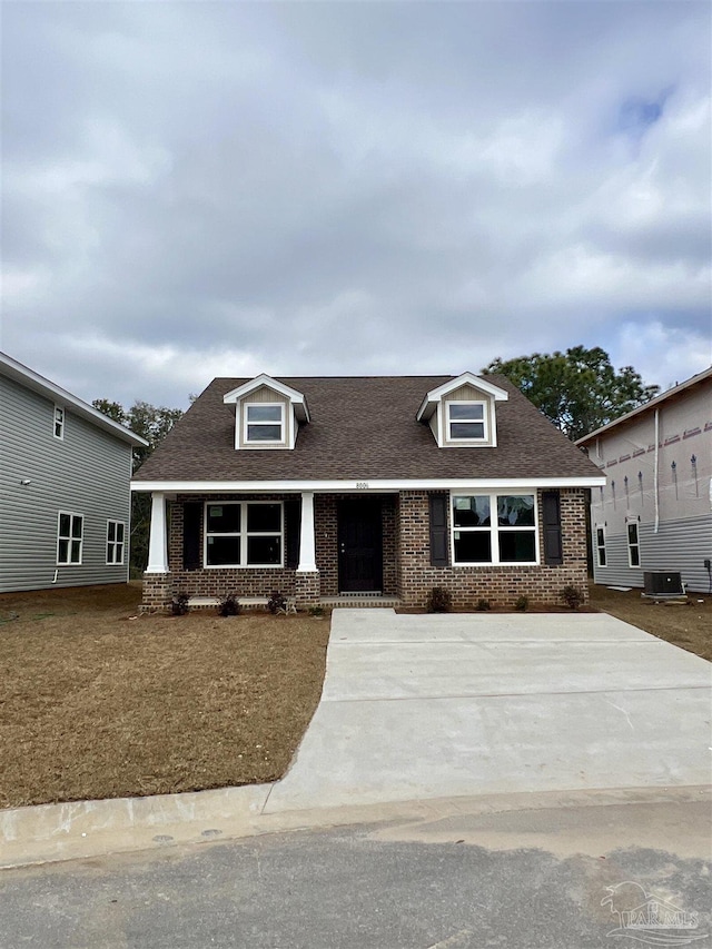 view of front of home with roof with shingles, cooling unit, and brick siding