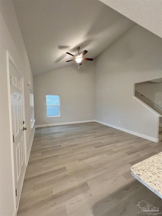 unfurnished living room featuring light wood-type flooring, high vaulted ceiling, and ceiling fan