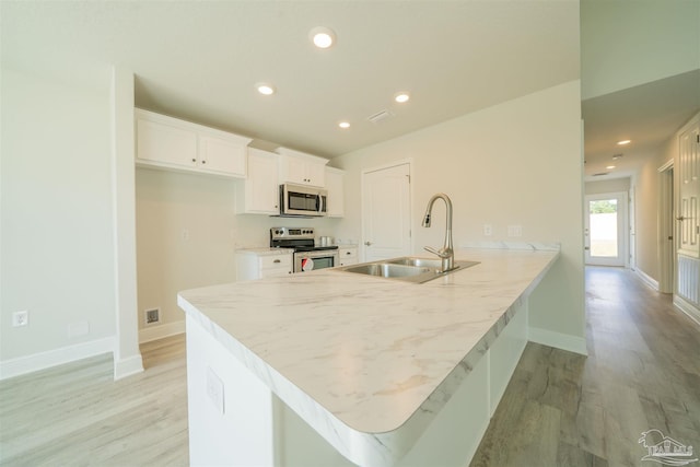 kitchen featuring appliances with stainless steel finishes, light hardwood / wood-style flooring, white cabinetry, and sink