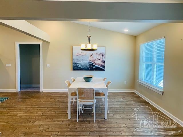 unfurnished dining area featuring wood-type flooring, lofted ceiling, and a notable chandelier