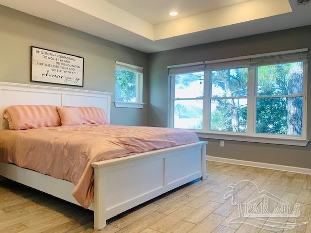 bedroom featuring light wood-type flooring and a tray ceiling