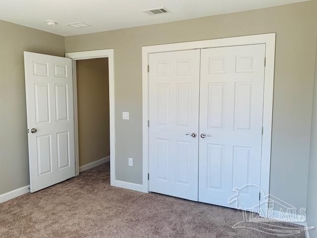 unfurnished bedroom featuring light carpet and a closet