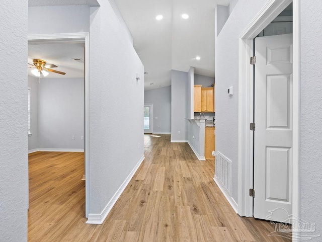 hallway featuring light wood-type flooring, visible vents, and baseboards