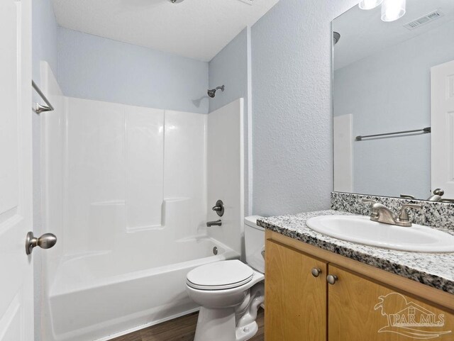 full bathroom with visible vents, bathing tub / shower combination, toilet, wood finished floors, and vanity