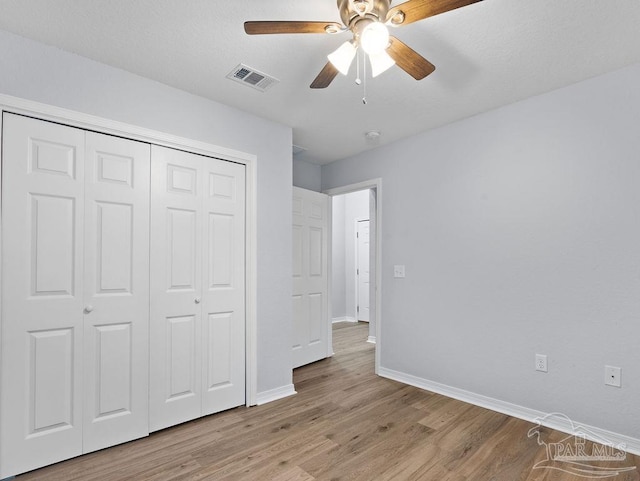 unfurnished bedroom with baseboards, visible vents, a ceiling fan, light wood-style floors, and a closet